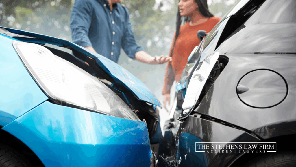 blue car hit a black car in a rear-end collision and two people are arguing about the accident