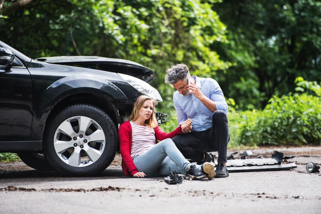 young woman sitting on the ground after a car accident
