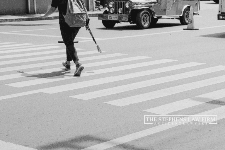 Person crossing a crosswalk with cars waiting to pass in the background